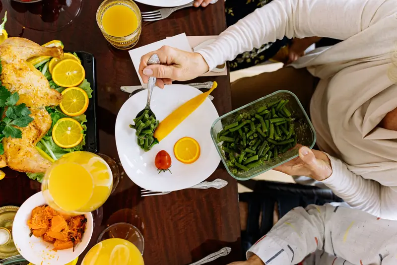 Top view of a festive meal setting with citrus, vegetables, and roasted chicken